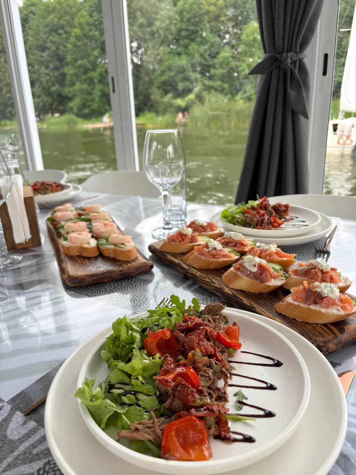Кейтеринг с закусками и салатами на столе внутри хаусбота у воды