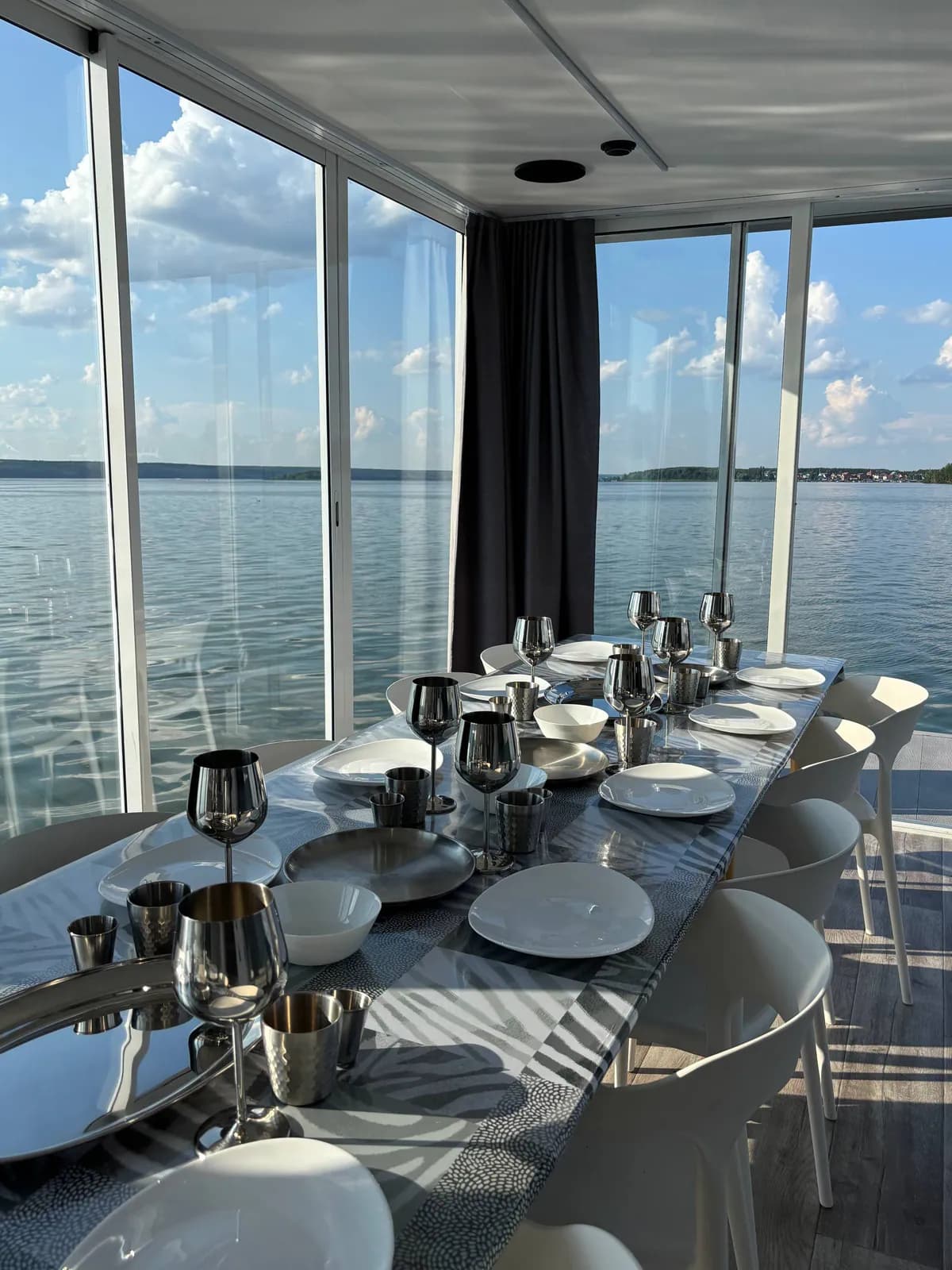 Сервированный стол у панорамных окон хаусбота с видом на воду