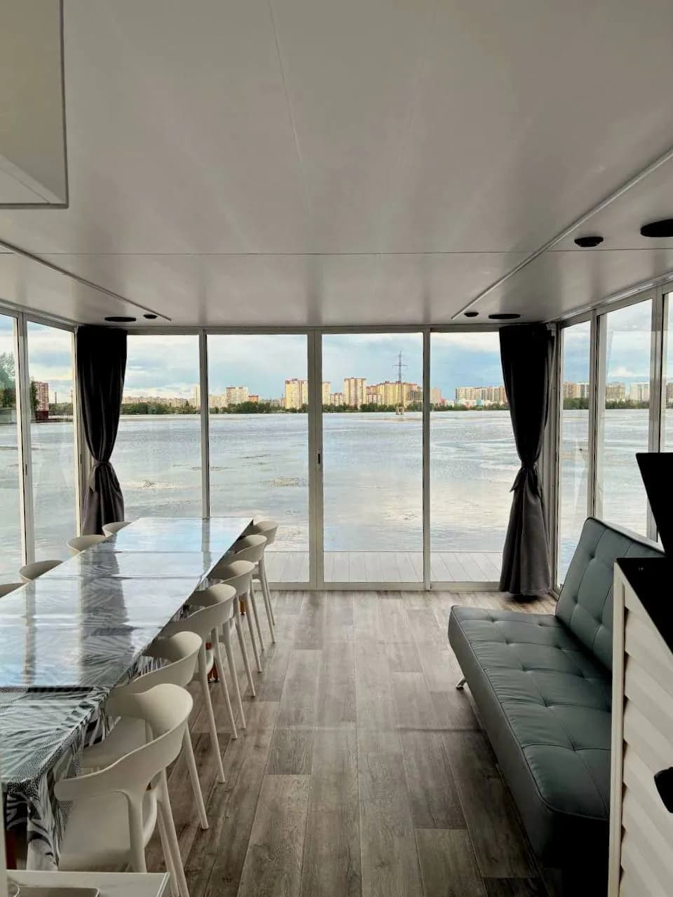 Просторный салон хаусбота с длинным столом, мягкой зоной и видом на воду