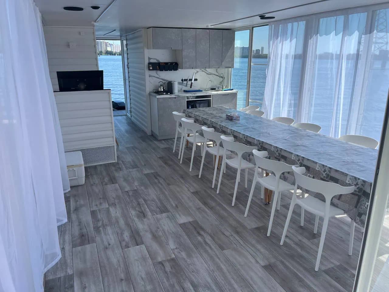 Интерьер хаусбота с кухонным блоком и большим столом у панорамных окон